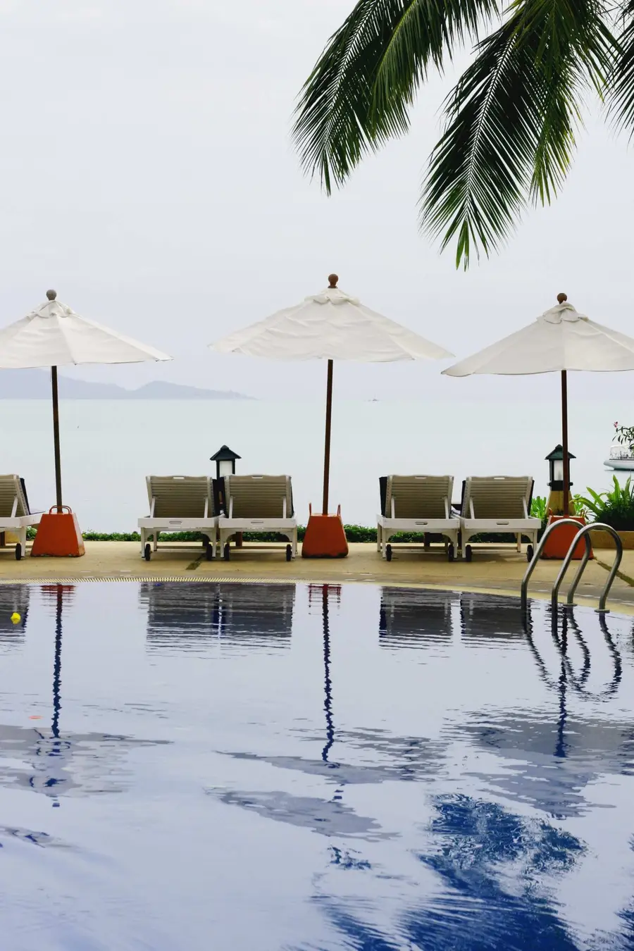 Loungers and umbrellas beside a resort swimming pool overlooking the water